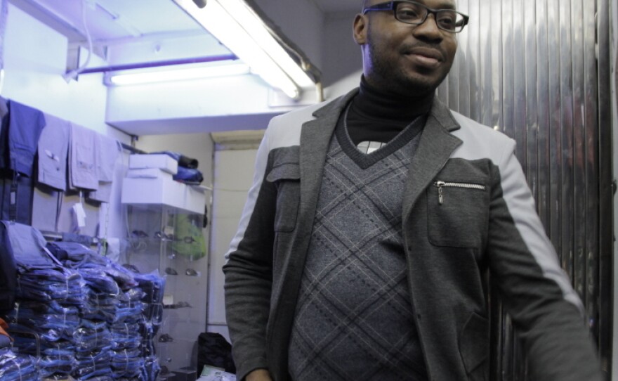 A trader who goes by the name Fortunato — he says it's his "designer name" — stands outside one of the clothing shops in the Little Africa section of Guangzhou. He's been living in the Chinese city for five years.