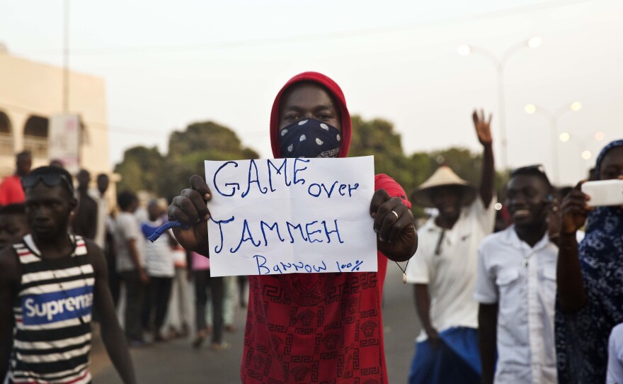 A man holds a banner Thursday as Gambians cheers in Serrekunda, Gambia.