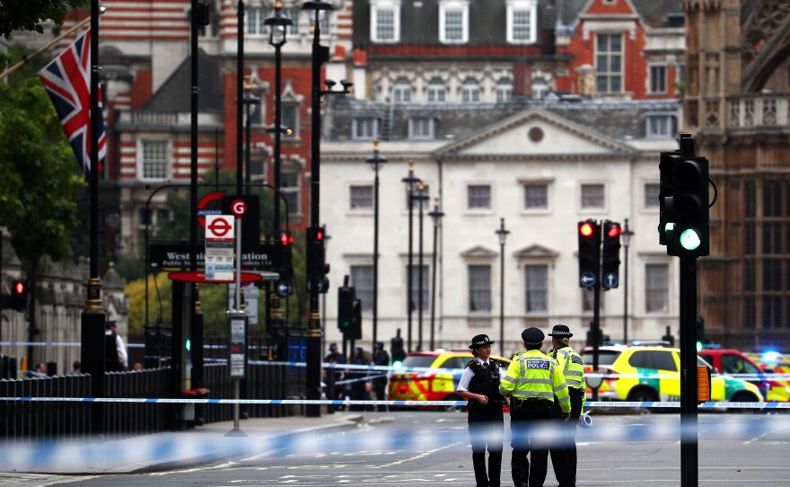 Police stand in the street after a car crashed outside the Houses of Parliament in Westminster, London, on Tuesday.