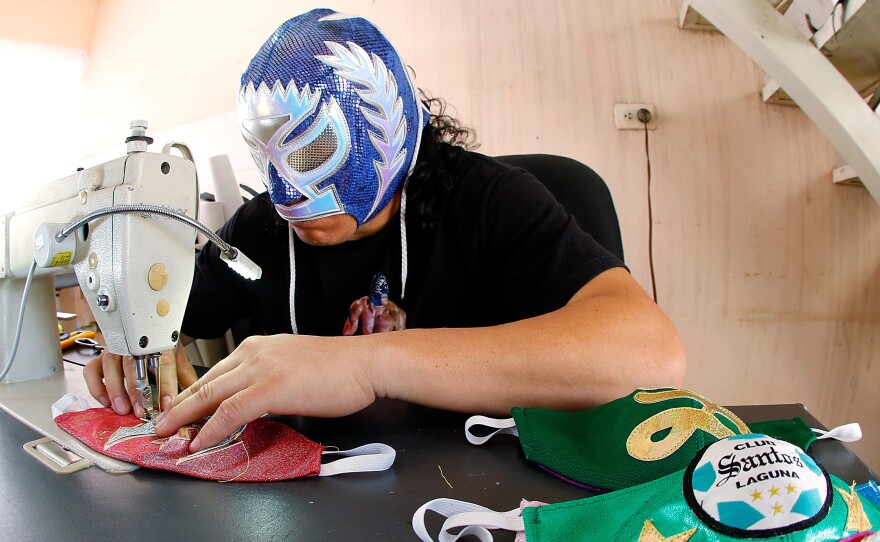 Mexican lucha libre wrestler Hijo del Soberano sews face masks since his matches have stopped due to the COVID-19 pandemic.