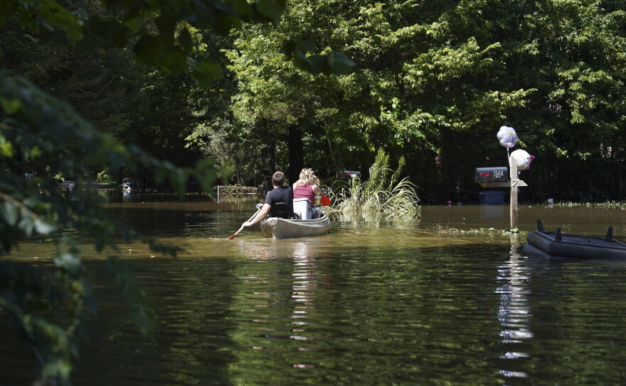 Residents paddle through a flooded neighborhood in a kayak in Indianapolis, Sunday, Aug. 16, 2026.