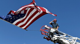 A captain with the Clifton Fire Protection District salutes the passing procession carrying the bodies of three firefighters killed while fighting the Snyder Fire in Grand Junction, Colo., on June 28.