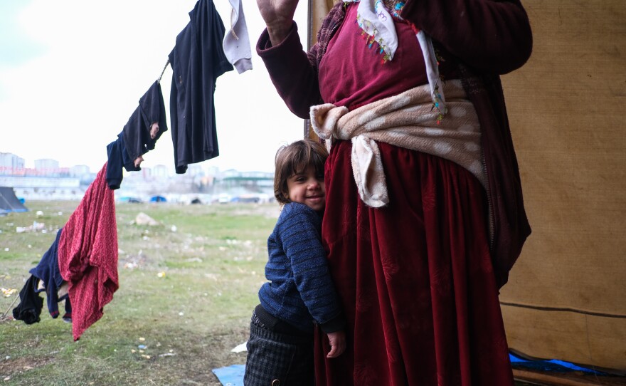 A 64-year old grandmother and her grandson in her daughter-in-law's tent at the makeshift migrant camp.