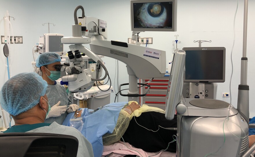 At St. John Eye Hospital in Gaza, a Palestinian surgeon removes a woman's cataract using surgery equipment branded with a sticker that says, in Arabic, "From The American People." U.S. funding subsidizes these surgeries for Palestinians who could not otherwise afford them, but funding cuts means subsidies will not continue, hospital administrators say.