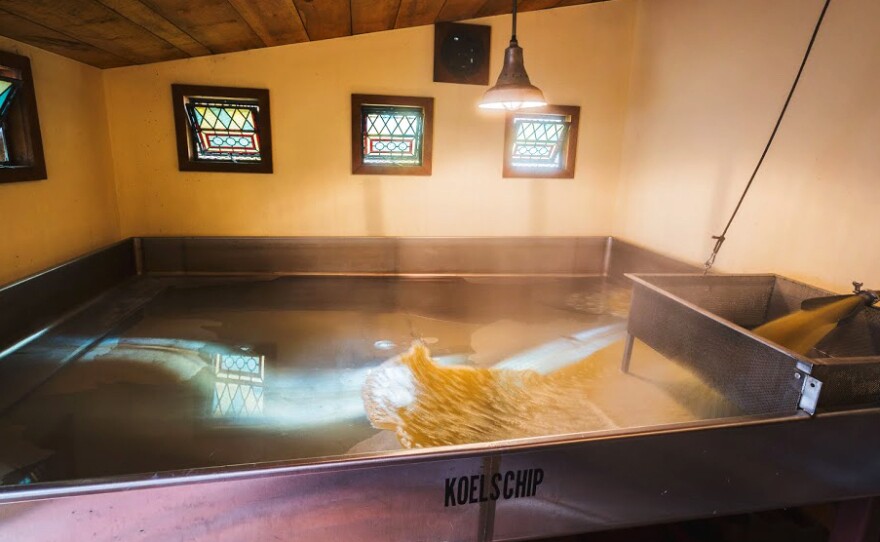 This is Allagash's coolship — an open, spontaneous fermentation tank with wort rushing in. When the Maine breeze passes over the liquid, wild yeast in the air around the brewery will begin to ferment the wort to make beer.