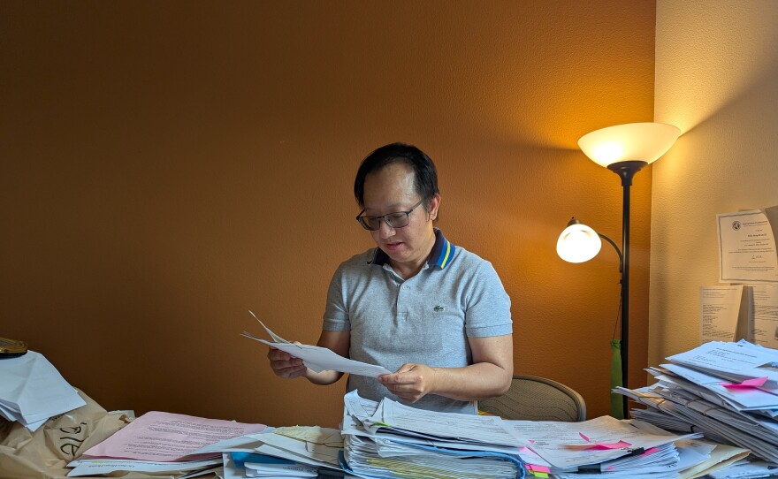 Dr. Allen Lee sifts through health insurance paperwork in his home on March 29, 2025.