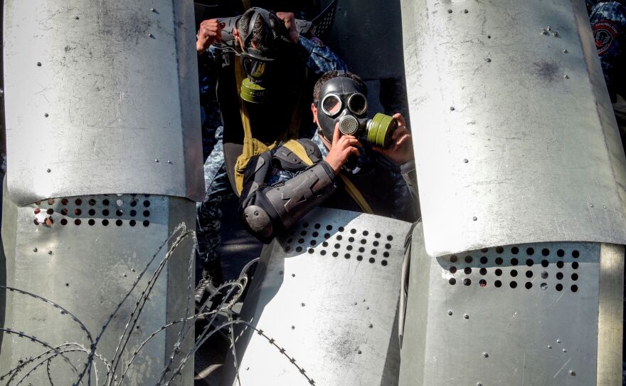 Armenian special police hunker down behind a barbed wire barrier in central Yerevan on Monday. According to <a href="https://www.hrw.org/news/2018/04/16/protests-surge-armenia">some witnesses</a>, used stun grenades against the protesters who sought to break through the barrier that blocked them from the parliament building.