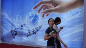 Visitors walk past a display depicting artificial intelligence and a human hand at the China International Supply Chain Expo in Beijing on June 22.