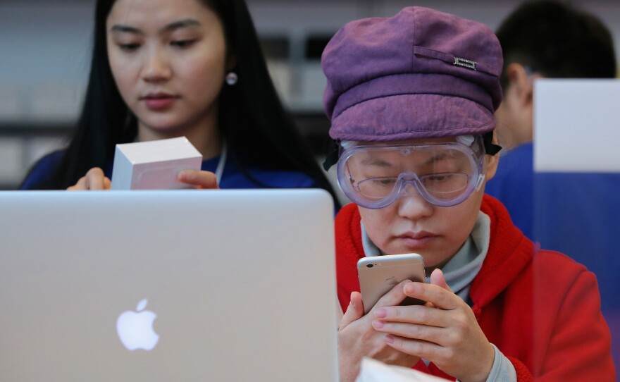 A customer sets up her new iPhone 6 at an Apple store in Beijing on Friday. A group says the Chinese government backed an attack against users of Apple's iCloud service, but the government denies the claim.