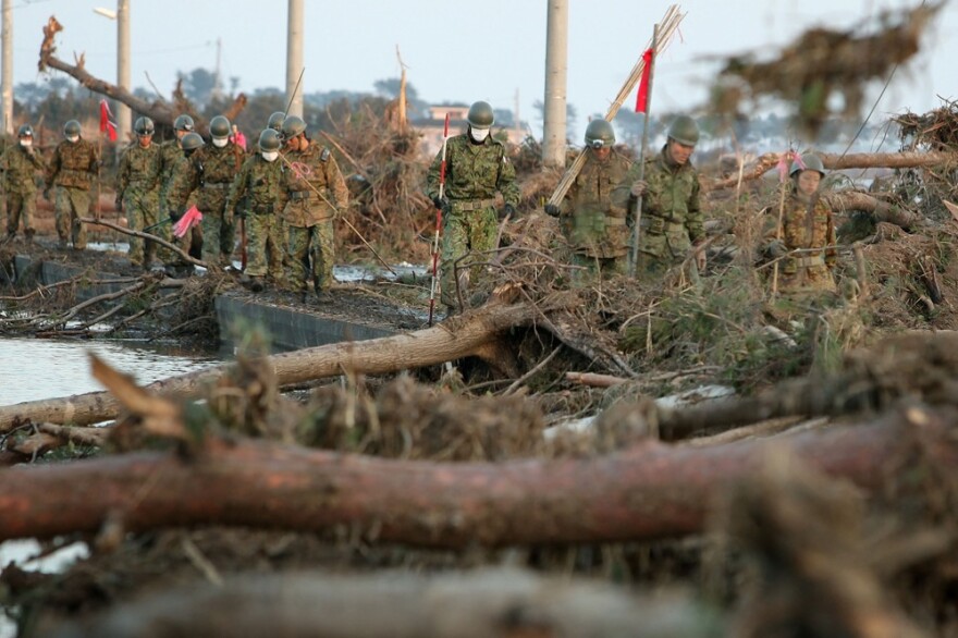 Members of the Japanese military walk through tsunami wreckage in Sendai, Japan on Sunday.