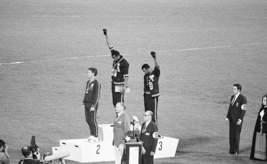 Tommie Smith and John Carlos, gold and bronze medalists in the 200-meter run at the 1968 Olympic Games, engage in a victory stand protest against unfair treatment of African-Americans in the United States. Australian Peter Norman is the silver medalist.