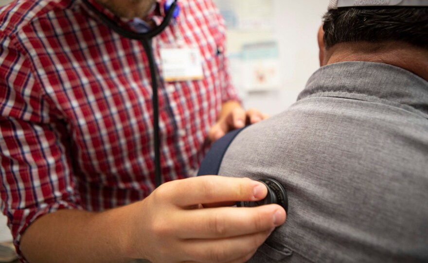 A physician's assistant listens to a patient's heartbeat at a clinic in Bieber, California. The Legislature's budget would expand Medi-Cal.