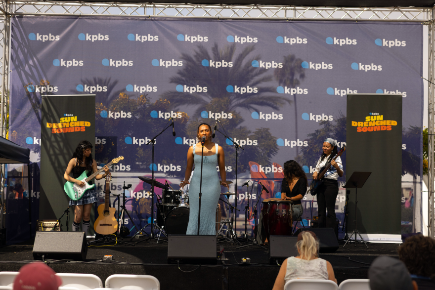 Nicole Hernandez, center, performs with Athalia Rodriguez on guitar, Sarah Brew on drums, Sahar Malik on congas and Angelica Yumi Pruitt on bass at the KPBS San Diego Book Festival as part of Sun Drenched Sounds on Aug. 22, 2026.