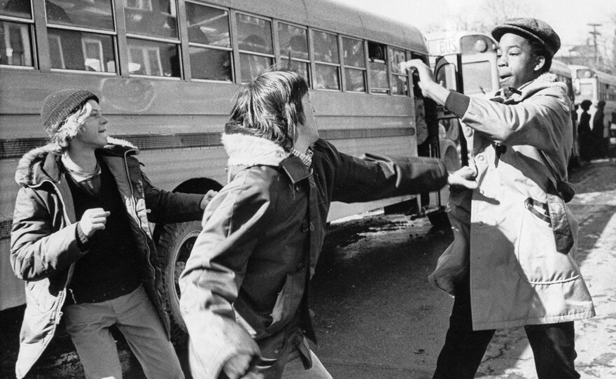 White and black students begin to fight outside Hyde Park High School in Boston, Mass., Feb. 14, 1975. The city of Boston started a court-ordered school integration program requiring the busing of 18 percent of public school students.