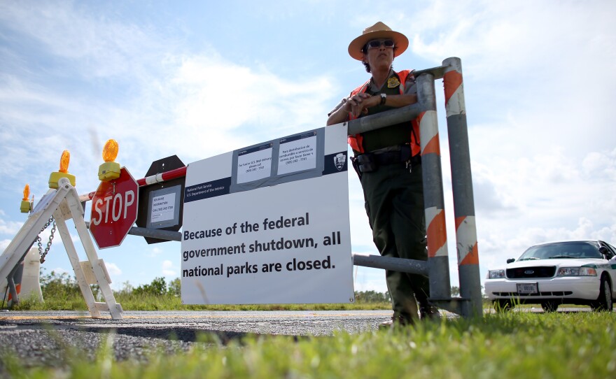 U.S. Park Ranger Mirta Maltes stands near the road-closed sign leading to the Everglades National Park on Oct. 7 in Miami.