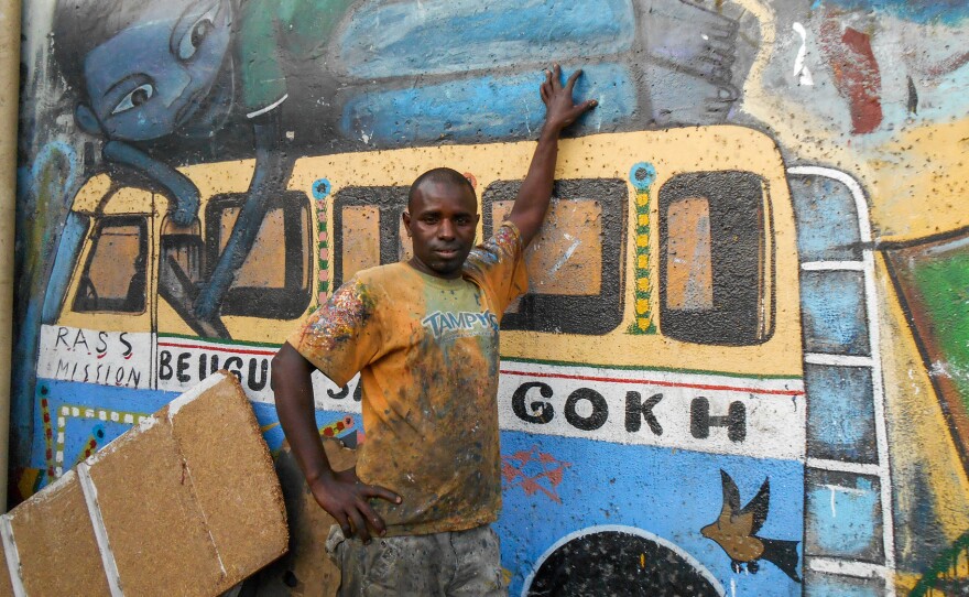 Kalidou Diallo, aka "Neyoo," is a car rapide painter who also does murals, like the one behind the bus.