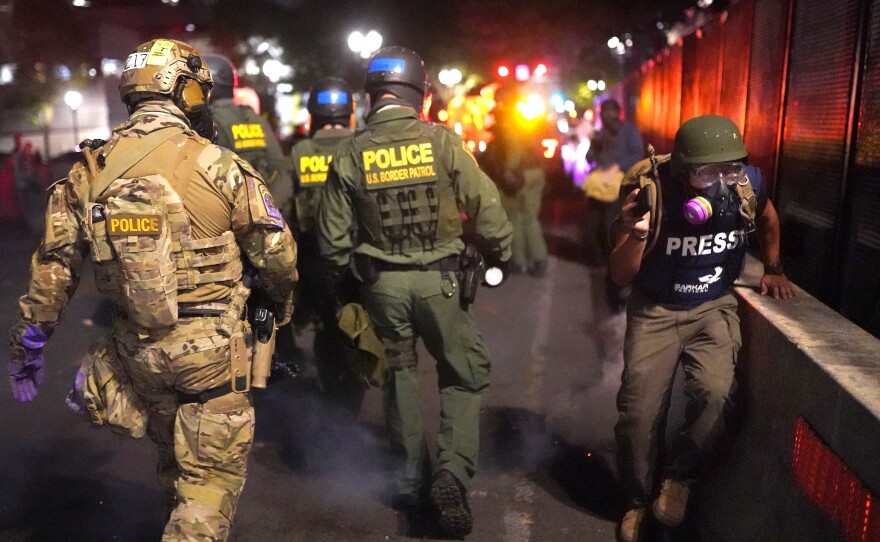 A journalist runs past federal officers after during a protest against racial injustice in front of the Mark O. Hatfield U.S. Courthouse on July 30, 2020 in Portland, Ore.