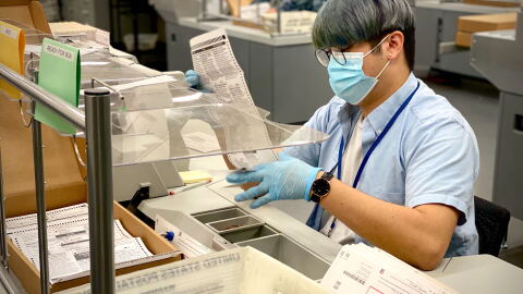 A worker at the San Diego County Registrar of Voters checks a mail-in ballot for errors in this Oct. 16, 2020 photo.