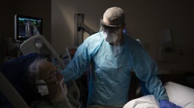 In this July 7, 2020, file photo, Spencer Cushing, 29, tends to David Feinour, a 71-year-old COVID-19 patient, at St. Jude Medical Center in Fullerton, Calif.
