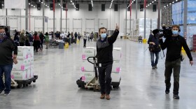 A worker gives a thumbs up while transporting boxes containing the Moderna COVID-19 vaccine to the loading dock for shipping at the McKesson distribution center in Olive Branch, Miss., Sunday, Dec. 20, 2020.
