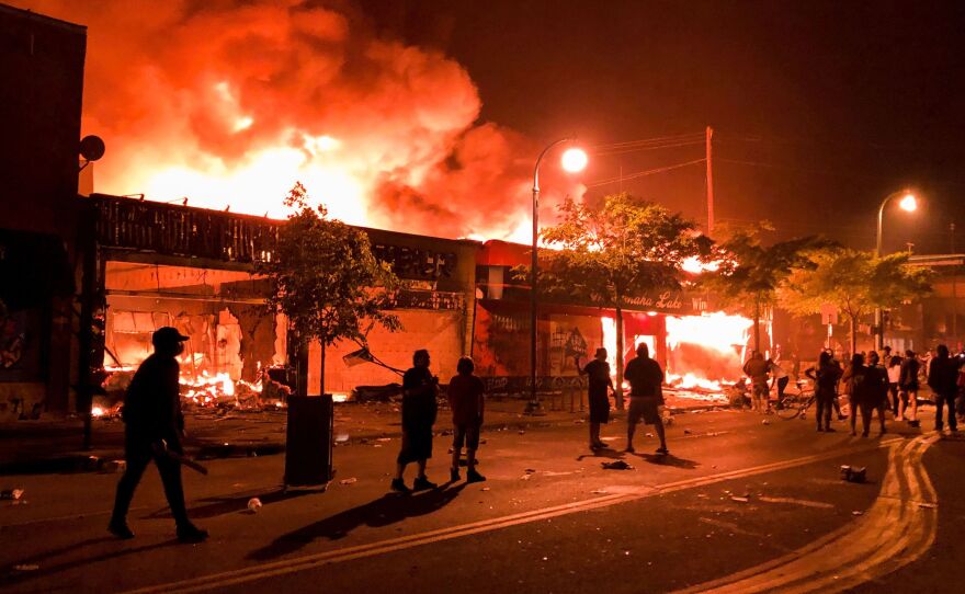 Flames rise from a liquor store and shops near the Third Police Precinct on May 28, 2020 in Minneapolis, Minnesota, during a protest over the death of George Floyd, an unarmed black man, who died after a police officer kneeled on his neck for several minutes.