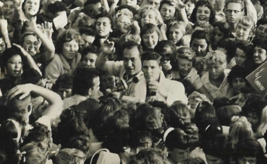 Laboe waves next to actor-musician Ricky Nelson (center, in the white blazer) amid a mob of fans in 1957.