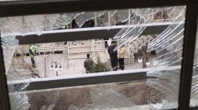 Iranian security agents are seen through a shattered window after Iranian nuclear engineer Massoud Ali Mohammadi was killed outside his Tehran residence when a booby-trapped motorcycle exploded on Jan. 12, 2010.