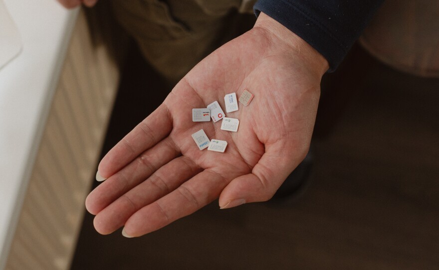 Gao Zhi displays cellphone SIM cards left behind by Wang Jingyu and Wang's girlfriend. Gao says he hosted the couple in his home for six months. He says Wang conned his family out of its life savings, which Wang denies.