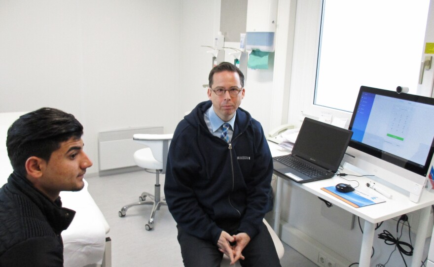 Iraqi asylum seeker Maher Murad (left) sought help from Dr. Martin Scherer for a sore throat. In the exam room, Scherer worked online with an Arabic-speaking translator.