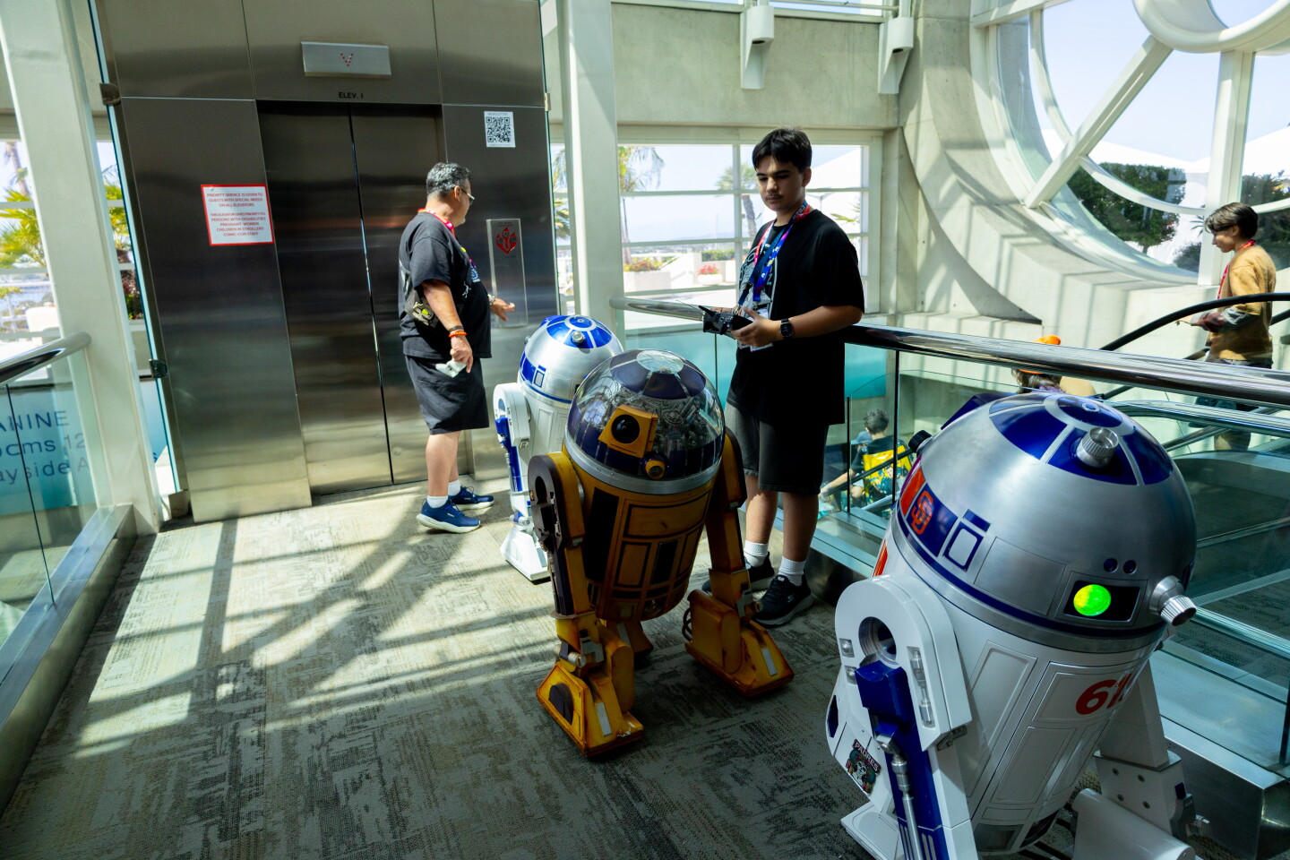 A group of C3 droids wait in line for the elevator at Comic-Con, April 23, 2026.