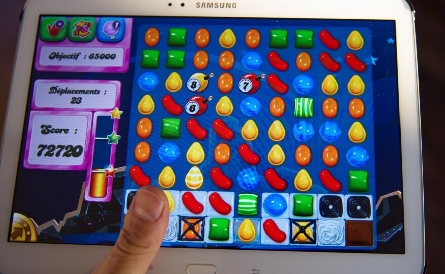 A person plays Candy Crush Saga on his tablet on March 6, 2014, in Lille, northern France. This year, mobile games revenues are expected to fly past console games and hit more than $30 billion worldwide.