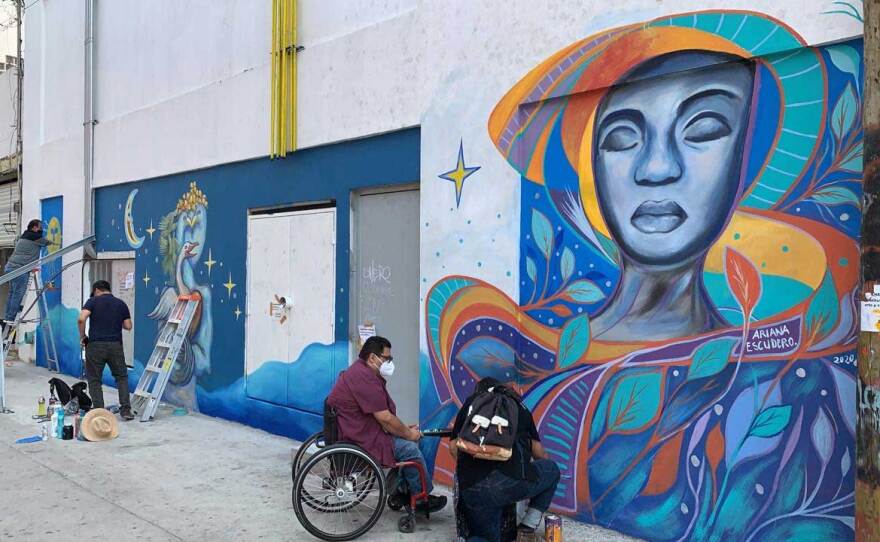 Artists work on Ariana Escudero's mural in Tijuana on September 11, 2020 for the "Walls/Muros" cross-border project.