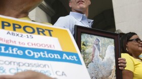 In this Sept. 24, 2015, file photo, Dan Diaz holds a photo of his late wife, Brittany Maynard, taken on their wedding day, during a rally calling for California Gov. Jerry Brown to sign right-to-die legislation at the Capitol in Sacramento, Calif. 