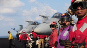 Sailors stand by while an F/A-18 Hornet launches from the flight deck of Nimitz-class aircraft carrier USS Dwight D. Eisenhower (CVN 69).