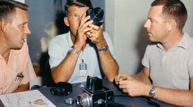 Astronaut Walter Schirra, center, checks out his spacecraft's camera equipment with Paul Becker of McDonnell, left, and Roland Williams of RCA.