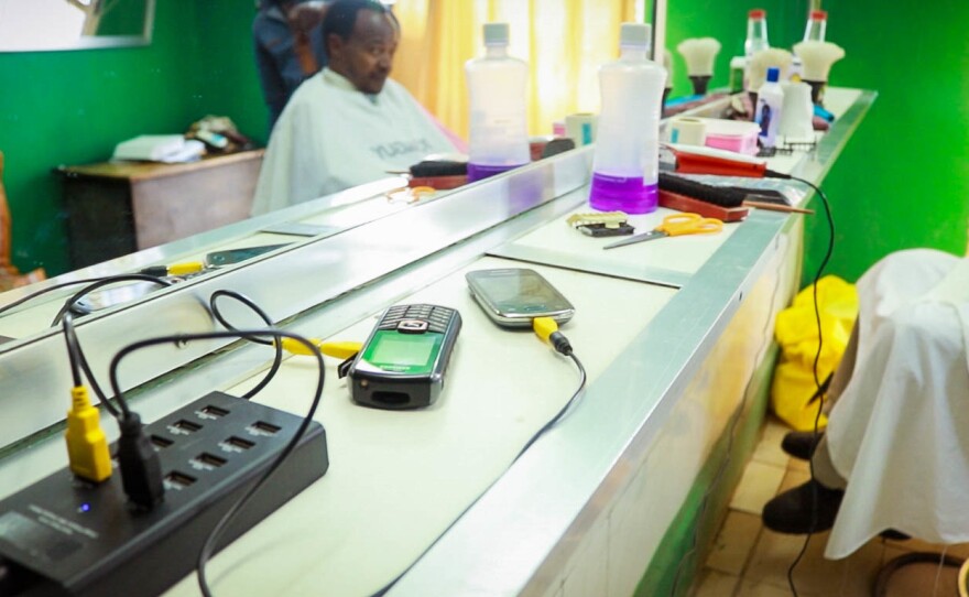 A solar-powered cellphone charger is part of a new program called "Kazi na Zola," which provides devices that can help small businesses — say, a barbershop — earn more revenue.