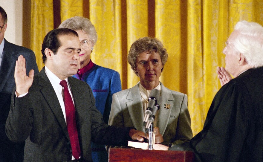 In this Sept. 26, 1986, file photo, retiring Chief Justice Warren Burger (right) administers an oath to Associate Justice Antonin Scalia, as Scalia's wife, Maureen, holds the bible during ceremonies in the East Room of White House.