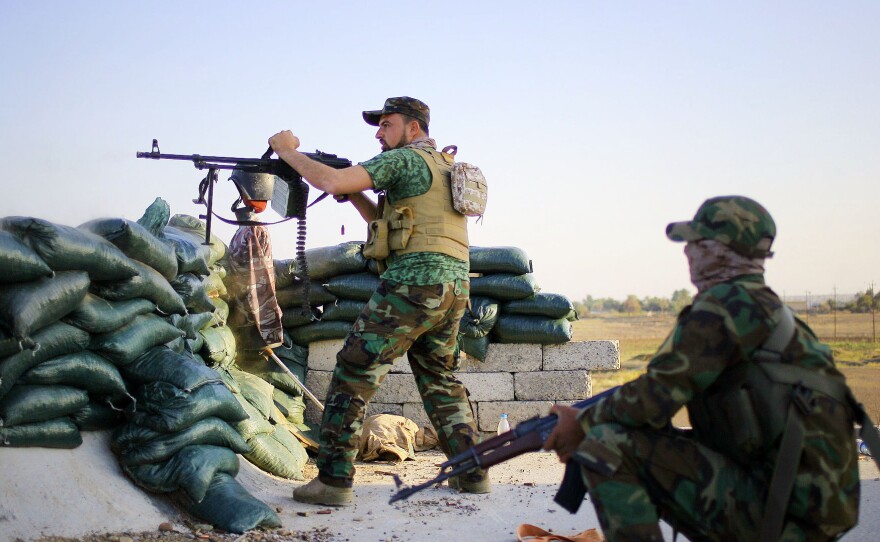 A volunteer fighter with a Shiite militant group known as "Jihad Brigades," aims his weapon during clashes with Islamic State group militants last month outside Tikrit, Iraq.