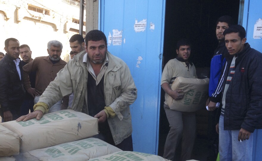 Men unload concrete in Gaza. Under a complicated system meant to prevent militants from getting cement to use for tunnels, Palestinians must get approval from home inspectors to buy just one sack.