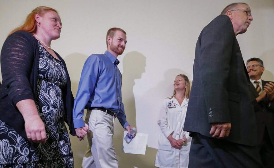 Ebola virus survivor Dr. Kent Brantly (center) and his wife, Amber (left), walk at a news conference at Emory University Hospital in Atlanta Thursday. Brantly and aid worker Nancy Writebol were discharged from the hospital less than a month after they contracted Ebola while treating patients in Liberia.