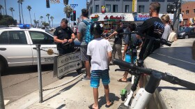 A tourist gets a ticket after kids were seen riding on dockless scooters at Mission Beach, July 29, 2019.