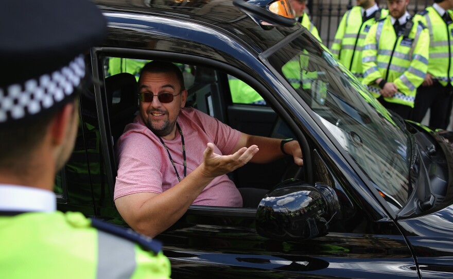 A London taxi driver speaks with police officers during a protest against Uber on Wednesday.