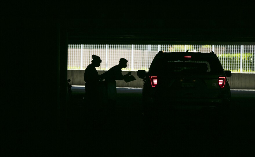 In this July 16, 2020, file photo, two physician assistants work at a COVID-19 drive-thru testing site set up at the Anaheim Convention Center in Anaheim, Calif.