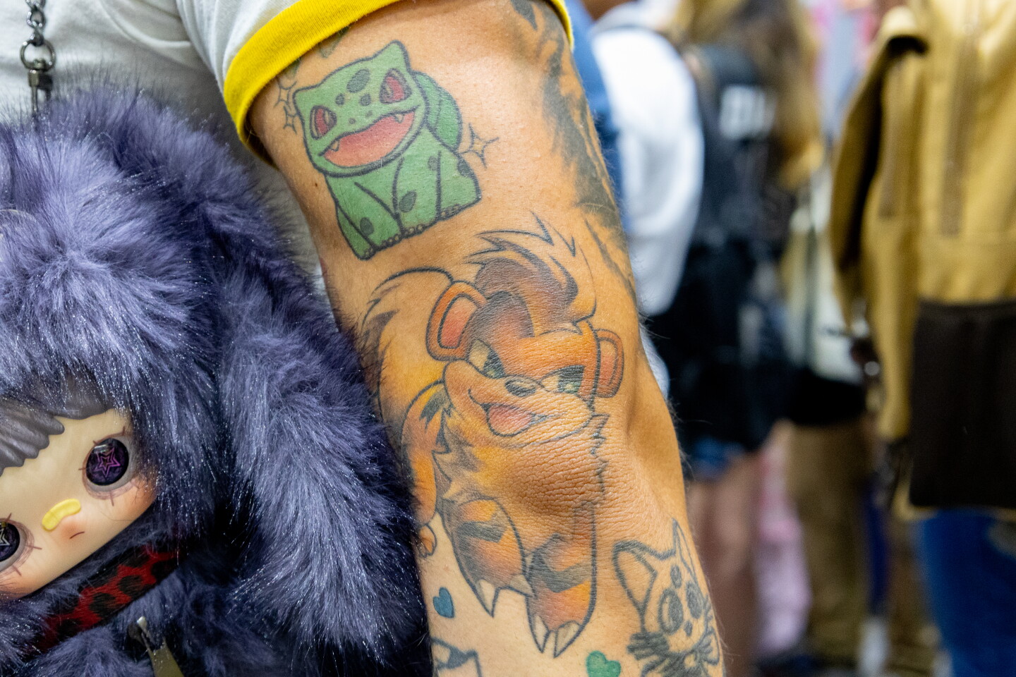 Pokémon tattoos featuring Bulbasaur and Growlithe smiling brightly on an attendee is shown at Comic-Con, July 23, 2026.