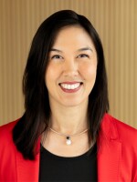 Woman smiling at camera with dark hair and red suit