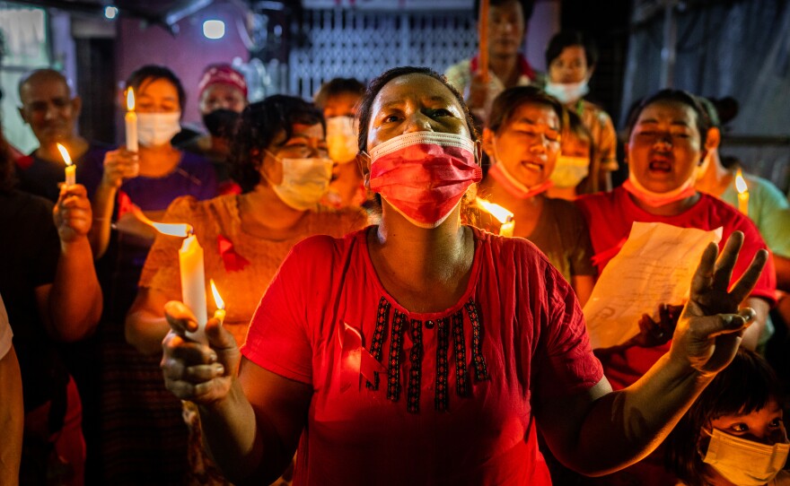 People hold candles and make a three-finger salute in a market on Feb. 5 in Yangon, Myanmar. People in Myanmar continue to take part in acts of civil disobedience in protest against the Feb. 1 military coup.