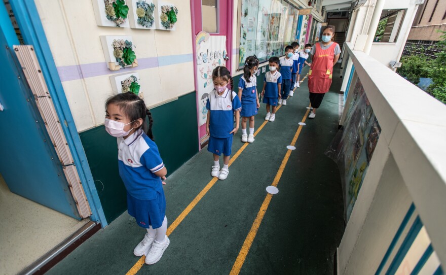 Children line up along socially distanced dots on the ground to go to the bathroom at Tsung Tsin Primary School and Kindergarten.
