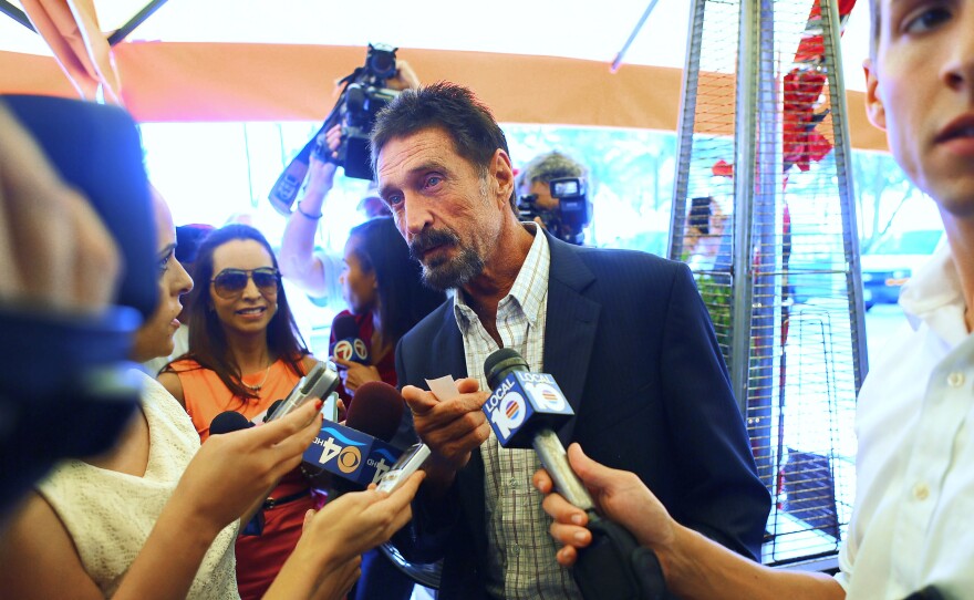 John McAfee talks to the media outside Beacon Hotel where he stayed after arriving from Guatemala in December 2012 in Miami Beach, Fla. McAfee was found dead in a Spanish prison cell on Wednesday, according to his lawyer.