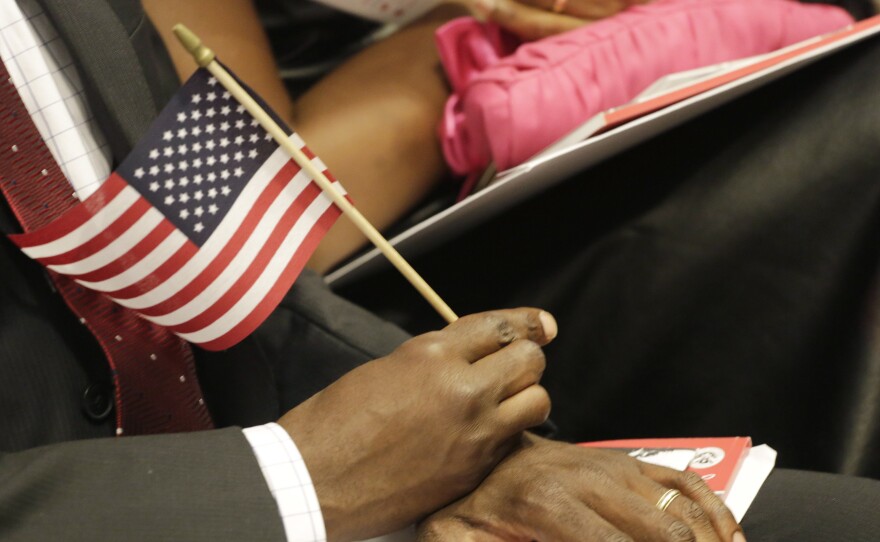 A new U.S. citizen holds an American flag during a naturalization ceremony in July. An Arizona law will require graduating high school seniors to pass the same civics test given to candidates for U.S. citizenship.