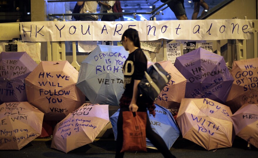 A woman walks past umbrellas with pro-democracy slogans written on them at a protest site near Hong Kong government headquarters on Saturday.